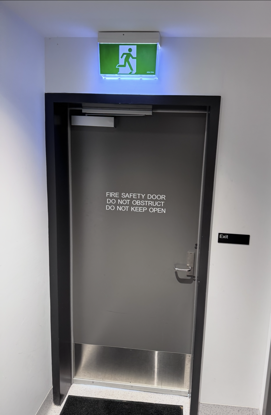 Grey fire safety door with do not obstruct signage and exit sign in a commercial building
