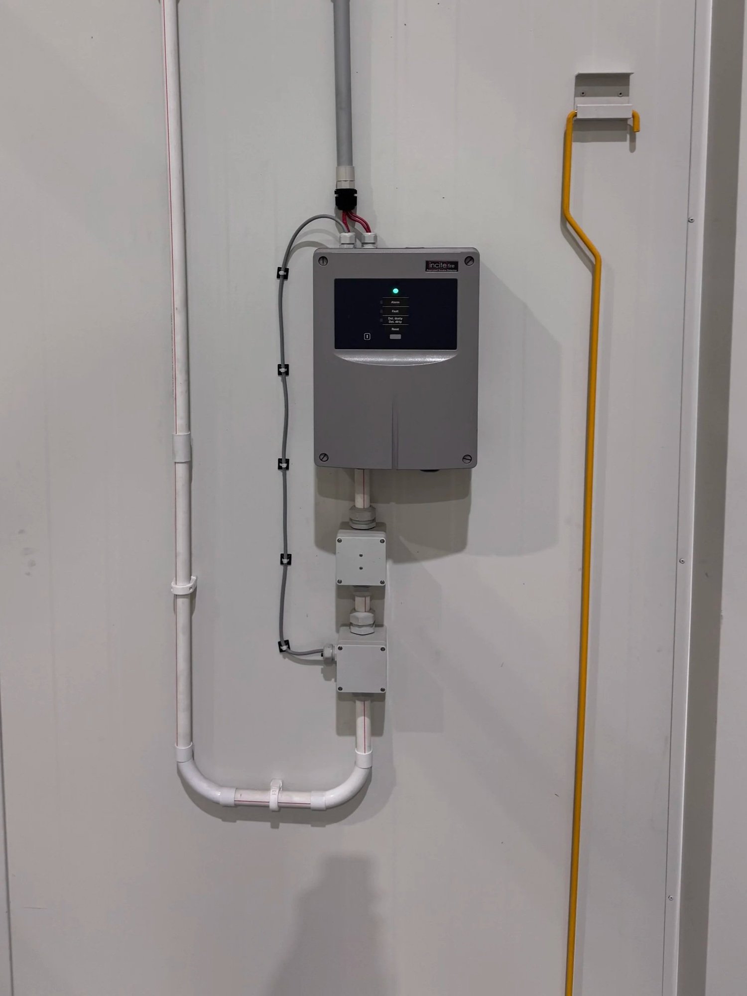 Fire detection panel and pipework in a residential building common area serviced by Safe QLD